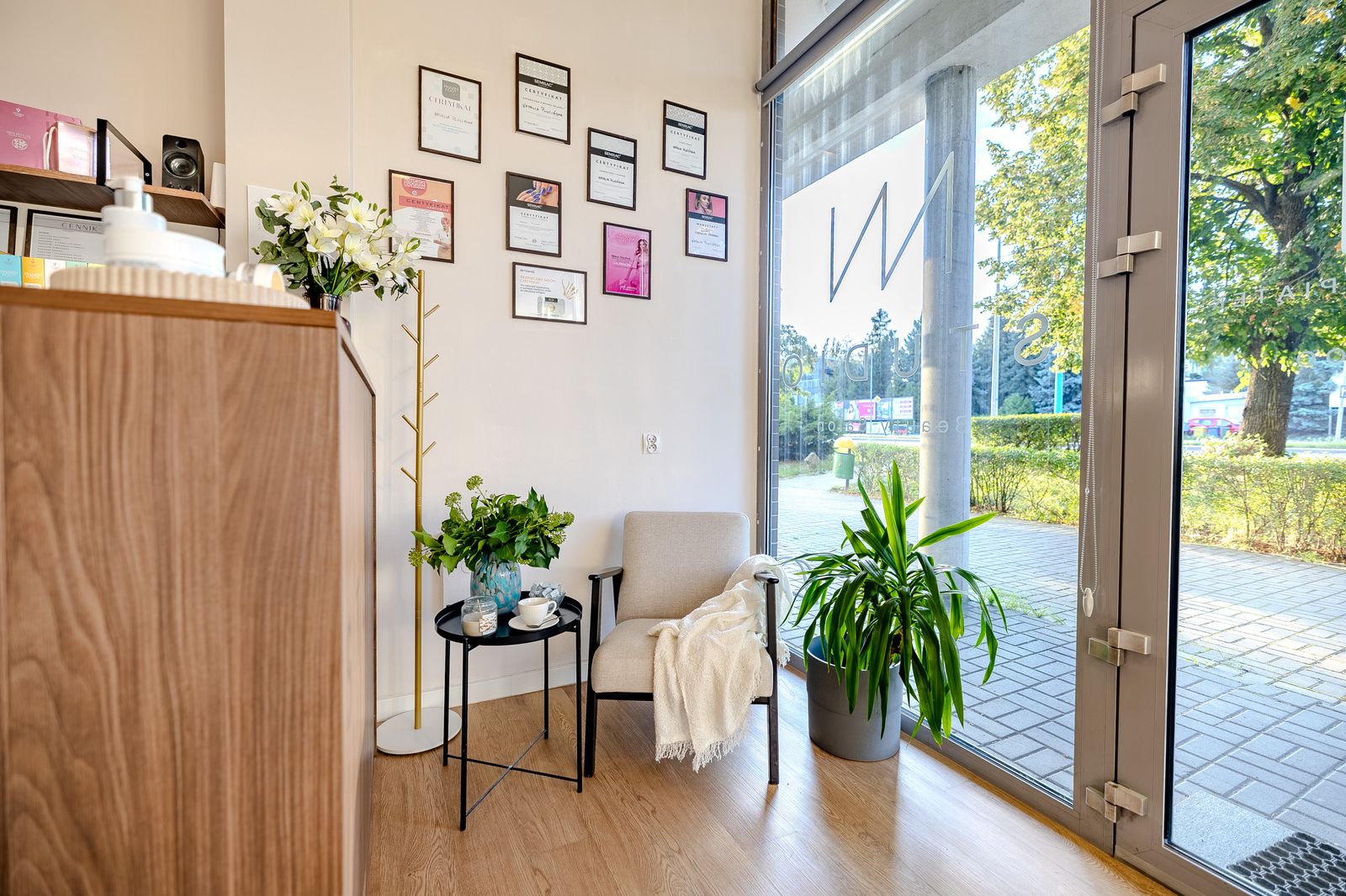 Fotel, kącik z herbatą i ściana z certyfikatami w salonie NN Studio